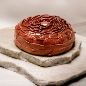 Gâteau rond au chocolat glacé décoré en spirale posé sur deux plaques de pierre.