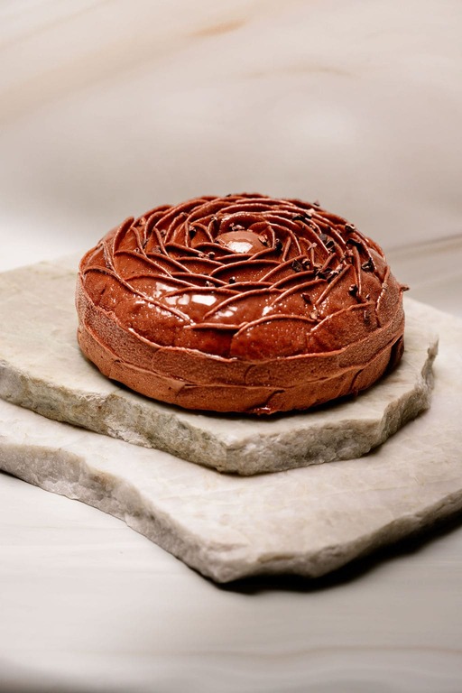 Gâteau rond au chocolat glacé décoré en spirale posé sur deux plaques de pierre.