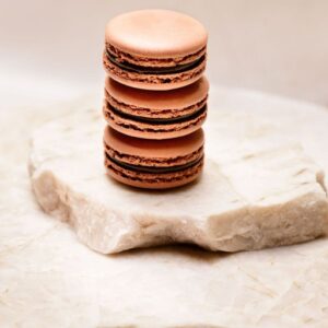 Trois macarons au chocolat empilés sur deux plaques de marbre clair.