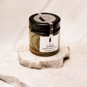 Pot en verre de cornichons tranchés au vinaigre Tonique Loft posé sur plaque en pierre blanche.