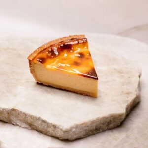 Part de flan pâtissier posée sur deux plaques de marbre blanc superposées.