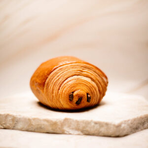 Pain au chocolat frais sur une plaque en pierre beige claire.