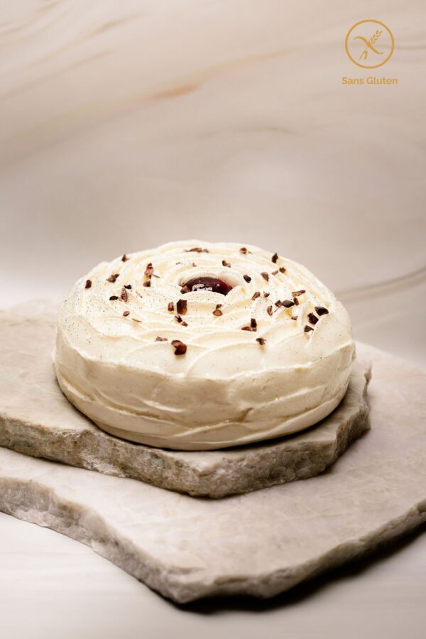 Gâteau rond sans gluten décoré de crème chantilly et éclats de cacao sur plaques de pierre.