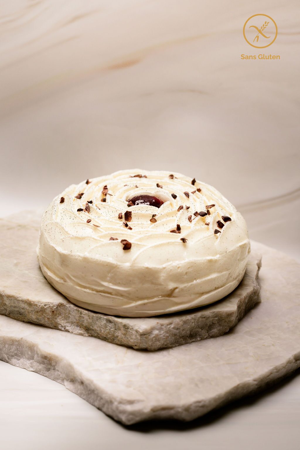Gâteau rond sans gluten décoré de crème chantilly et éclats de cacao sur plaques de pierre.