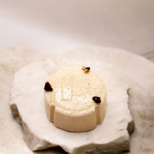 Petit dessert beige clair rond avec décor brun posé sur pierre blanche, label sans gluten.