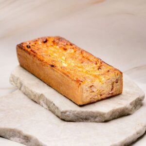 Quiche rectangulaire dorée posée sur deux pierres plates empilées.
