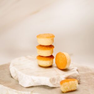Petits gâteaux ronds dorés empilés sur pierre blanche avec un gâteau coupé à côté