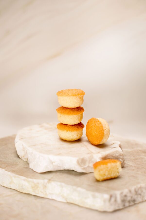 Petits gâteaux ronds dorés empilés sur pierre blanche avec un gâteau coupé à côté