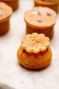 Petite pâtisserie ronde dorée avec décoration fleurie claire saupoudrée d'épices roses sur fond flou.