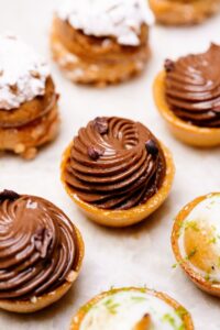 Mini-tartes décorées de crème au chocolat, crème blanche avec zestes verts et sucre glace