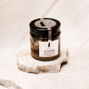 Pot en verre de tartinable aux champignons des bois sur une surface en marbre clair.