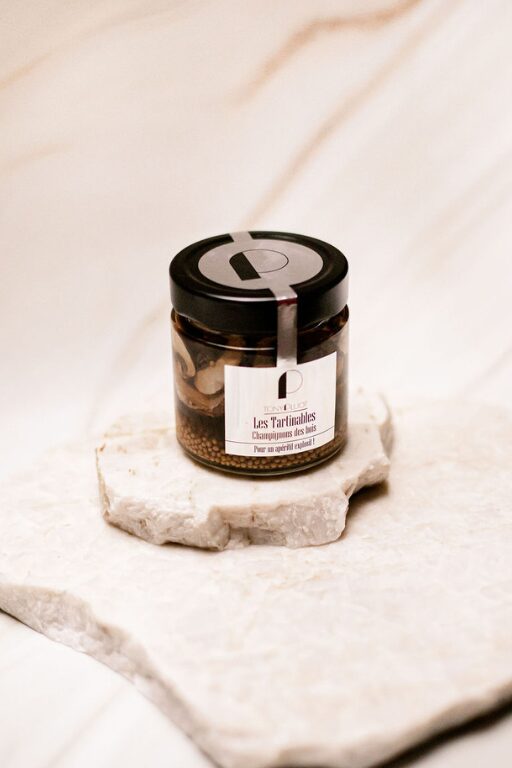 Pot en verre de tartinable aux champignons des bois sur une surface en marbre clair.