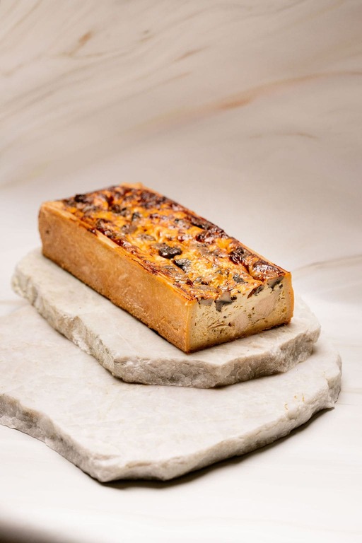 Pain de campagne rectangulaire aux champignons posé sur deux pierres plates en marbre.