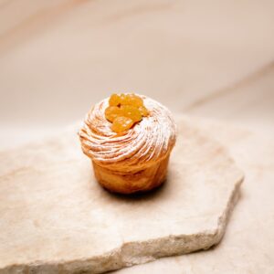 Petit gâteau feuilleté avec raisins dorés et sucre glace sur plaque de pierre beige.