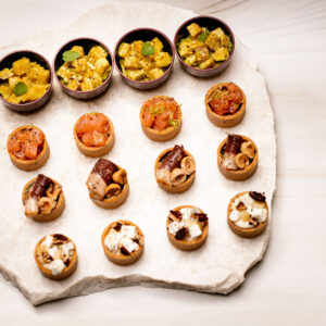 Plateau en pierre avec diverses bouchées apéritives en verrines et mini-tartelettes.