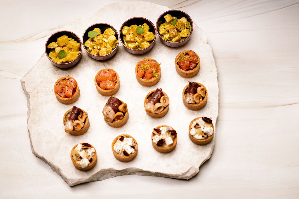 Plateau en pierre avec diverses bouchées apéritives en verrines et mini-tartelettes.