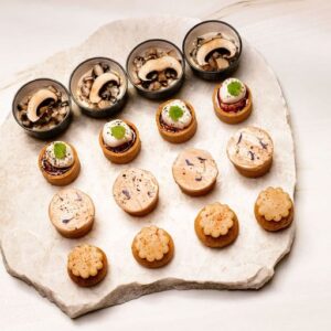 Plateau en pierre avec verrines champignons, mini-tartines, pâtés fleuris et biscuits fleurs.