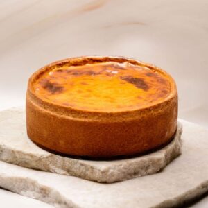 Tarte au fromage cuite avec croûte dorée posée sur plaques de pierre empilées.