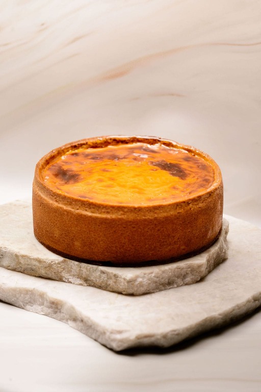 Tarte au fromage cuite avec croûte dorée posée sur plaques de pierre empilées.