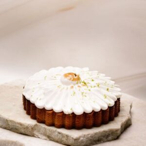 Tartelette sur deux pierres plates, crème blanche en pétales, zeste vert et caramel au centre.