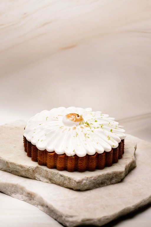 Tartelette sur deux pierres plates, crème blanche en pétales, zeste vert et caramel au centre.