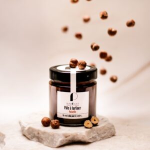 Pot de pâte à tartiner noisette Tony Pluot sur pierre avec noisettes entières autour.