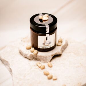 Pot de pâte à tartiner cacahuète Tony Pluot sur plaque blanche avec cacahuètes.