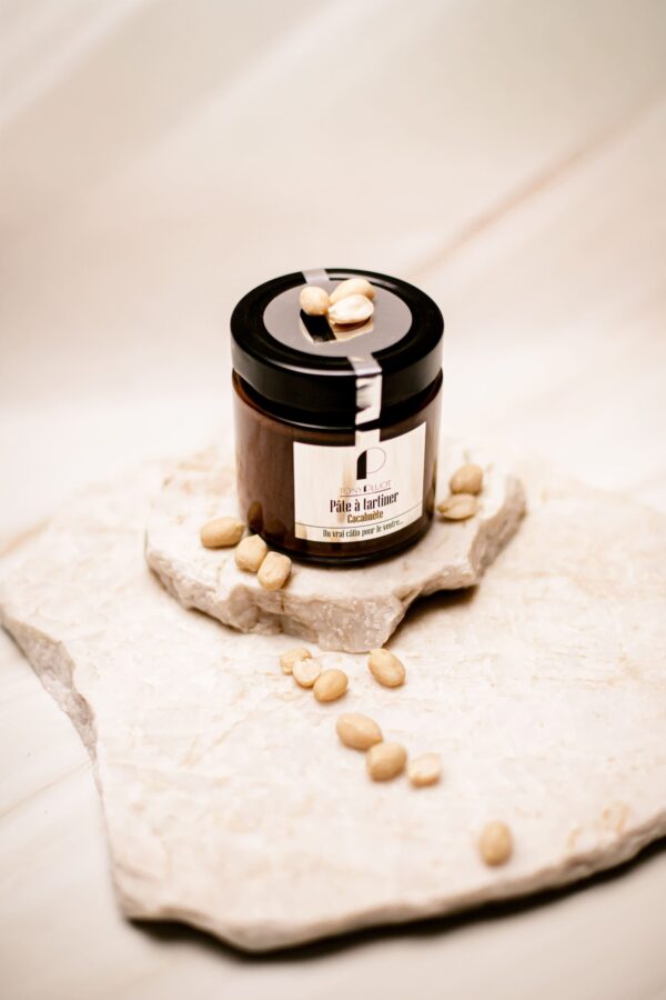 Pot de pâte à tartiner cacahuète Tony Pluot sur plaque blanche avec cacahuètes.