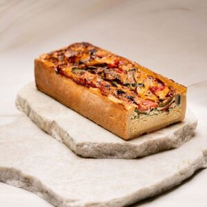 Tarte rectangulaire aux légumes variés sur pâte épaisse posée sur deux plaques de pierre.
