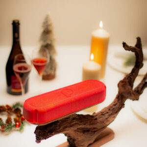 Dessert de Noël sans gluten_en forme de bûche et de capsule de champagne de couleur rouge avec des paillettes dorées sur un support artistique en chocolat sculpté