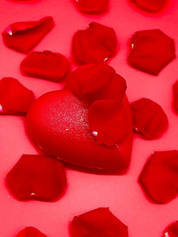 Fond rose, un gateau en forme de coeur rouge, petales de rose rouge pour la Saint-Valentin