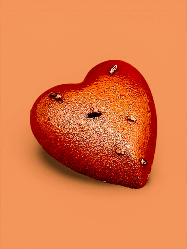 Sur un fond brun, un gateau en forme de cœur chocolat avec du grué de cacao pour la Saint-Valentin