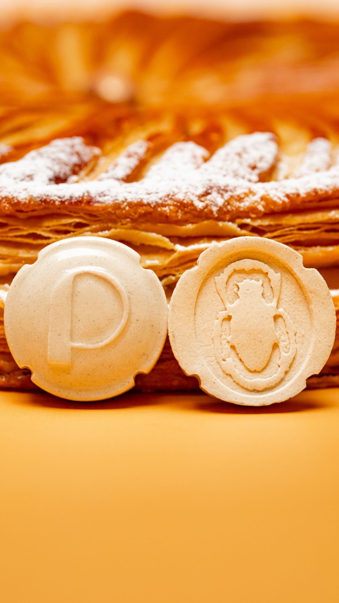 Dessert de Noël sans gluten en forme de bûche de couleur blanches avec des cubes oranges confits posé sur un marbre et un fond doré