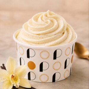 Pot de glace rond avec des lettres noires et dorées, rosace de glace pochée de couleur blanche de goût vanille avec des grains de gousses de vanille.