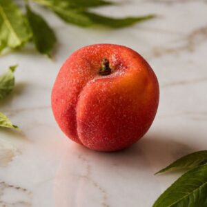 Ce fruit est une pêche de couleur rouge-orangé, posée sur un marbre.
